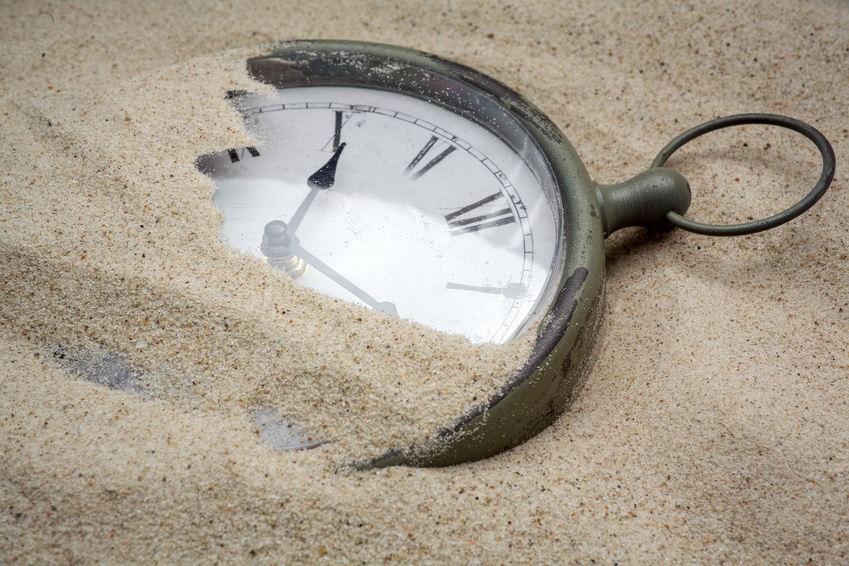 Time concept with a cklock on the sand