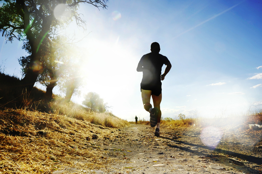 Silhouette of young sport man running off road cross country competition at summer sunset