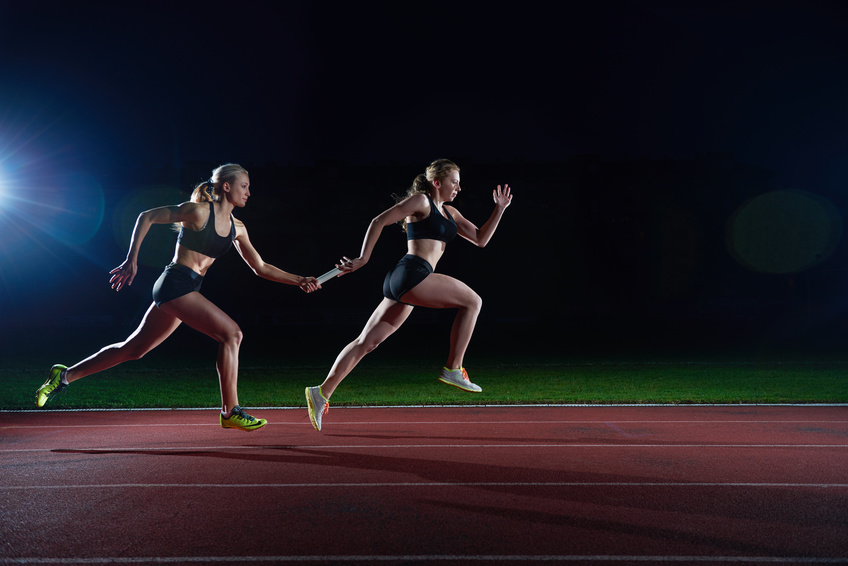 athletic runners passing baton in relay race